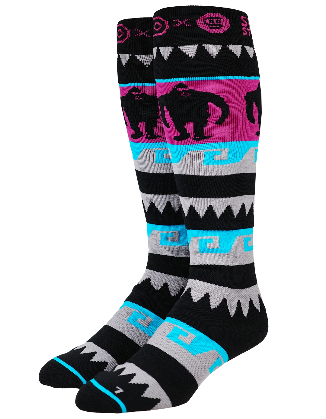 A pair of knee-high athletic socks with a black base and colorful geometric patterns in pink, gray, and turquoise blue. The socks feature a gorilla silhouette graphic on a pink band and a Greek key pattern.