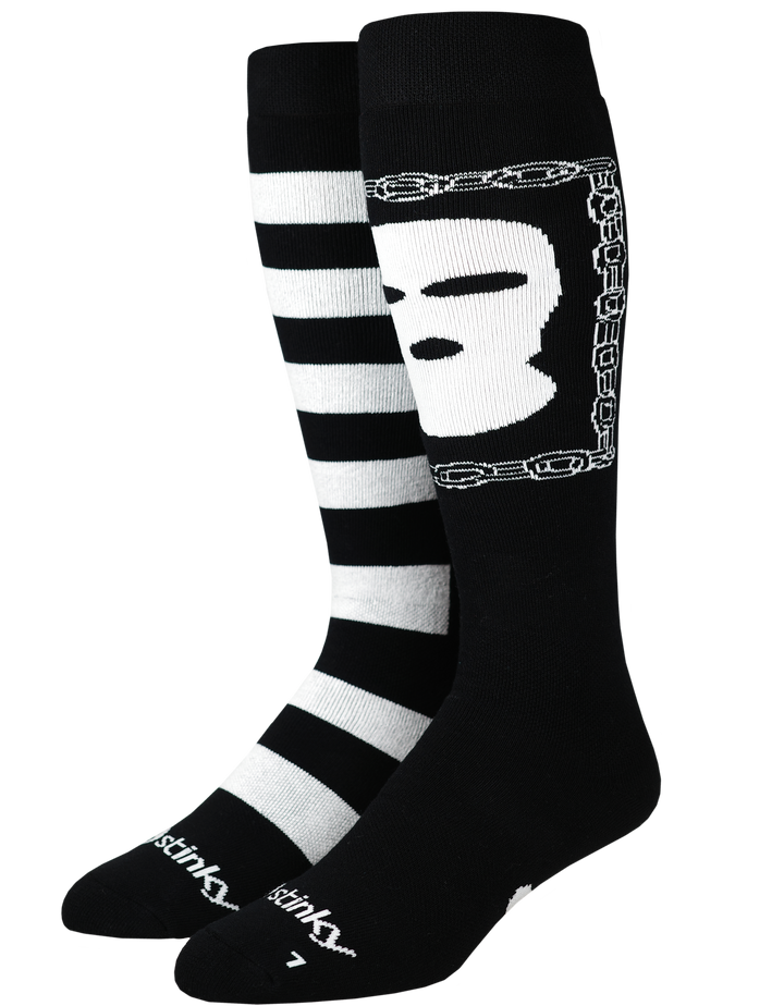 A pair of Stinky socks in black and white. One sock features horizontal black and white stripes, while the other features a white skull graphic enclosed in a chain design on a black background.