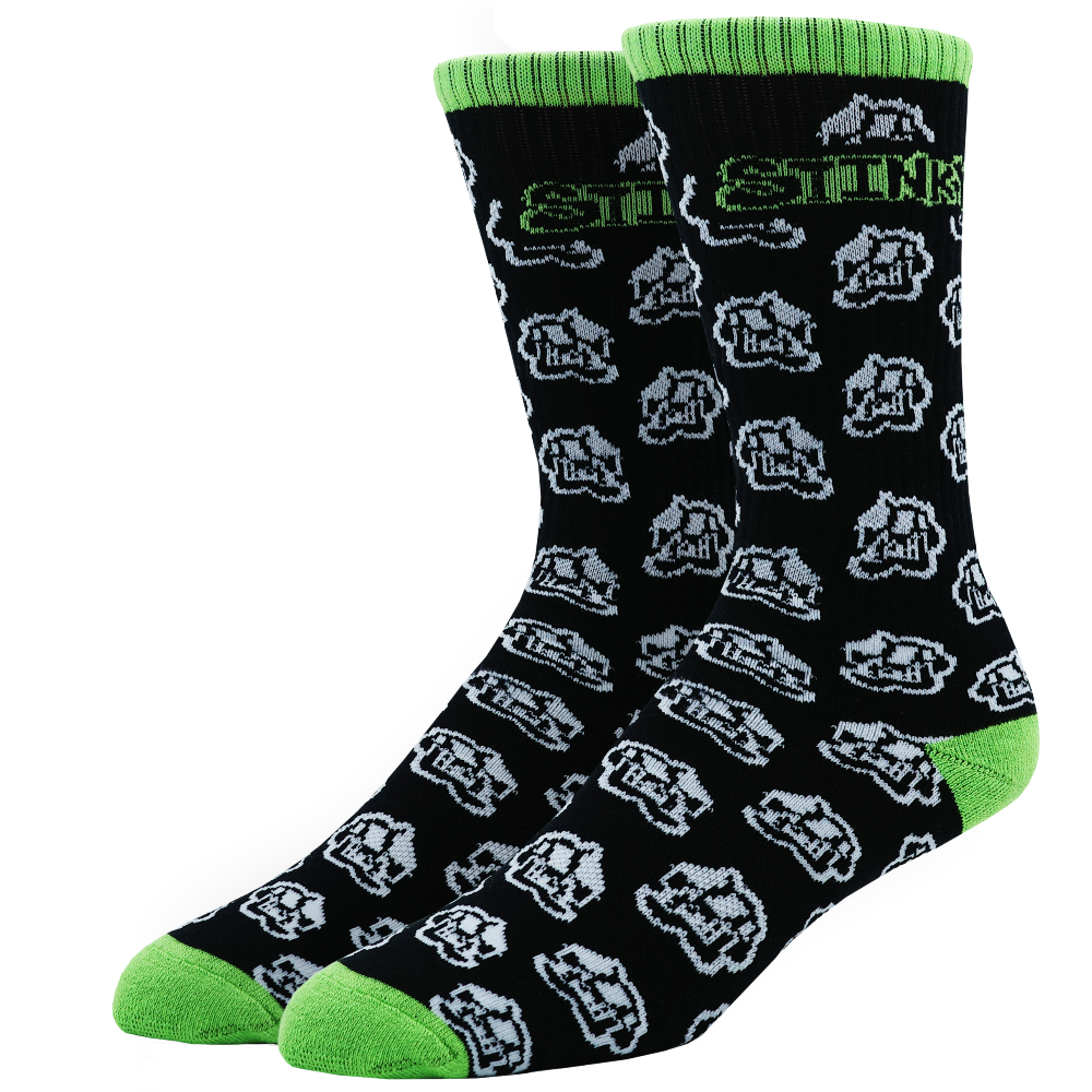 A pair of crew socks with a black background, featuring a repeating white and gray cartoon dog face pattern, bright green ribbed cuffs, green toes, and green heels. The word 'STOCK' is printed in green and white near the top.