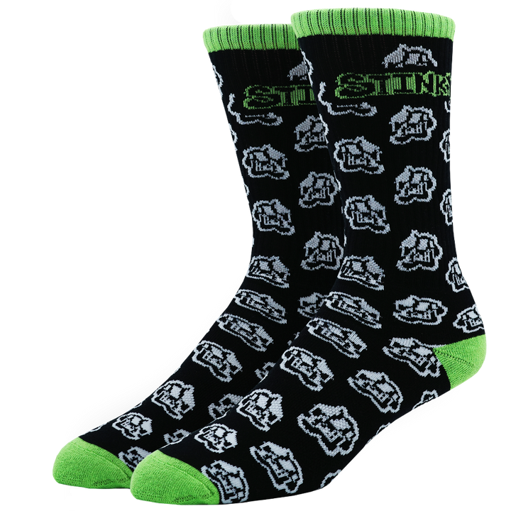 A pair of crew socks with a black background, featuring a repeating white and gray cartoon dog face pattern, bright green ribbed cuffs, green toes, and green heels. The word 'STOCK' is printed in green and white near the top.